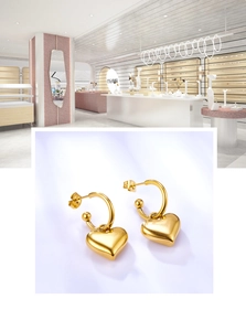 Detailed view of polished 18K gold heart-shaped drop earrings with a shiny metallic finish