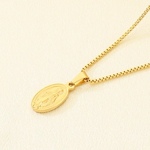 Macro shot of 18K gold plated oval Virgin Mary religious pendant on a box chain