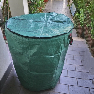 Detail view of 300L green garden waste bag with zipper lid and striped handle on pavement