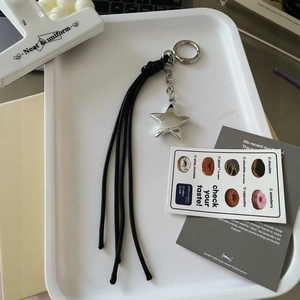 Y2K retro silver star keychain with long black leather tassel on a minimalist tray