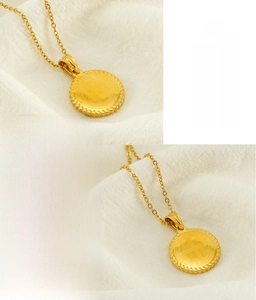 Detailed macro of gold vacuum plated stainless steel coin pendant with relief patterns