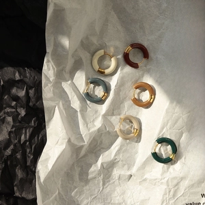 Detail of six enamel hoop earrings in various colors on textured artistic background