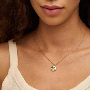 Detail of gold U-shaped lucky symbol necklace with cubic zirconia on a female model