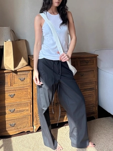 Detail view of black curved-leg work pants with white crossbody bag and casual styling