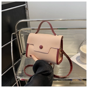 Detail of pink lychee textured PU leather handbag with contrasting burgundy handle and strap