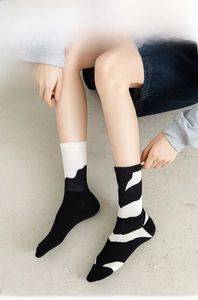 Close-up of knit crew socks with black and white asymmetric geometric wave patterns