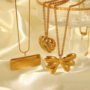 Detailed view of gold heart, butterfly, and square pendants on elegant beige silk background