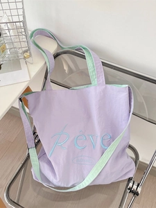 Purple canvas tote bag with green straps and Rêve embroidery on an acrylic chair