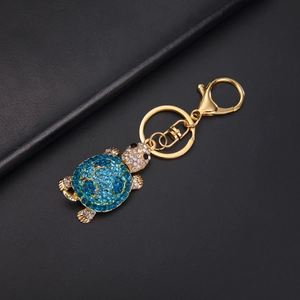 Close-up of sparkling blue and white rhinestones on a golden turtle keychain accessory