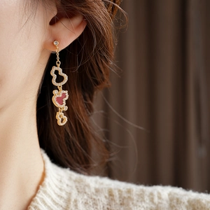 Detail of gold-plated gourd earrings with white crystals and long red tassels on model