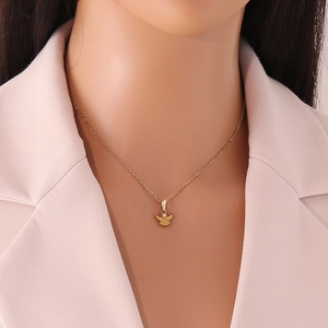 Goldene Engel-Halskette mit Zirkon-Anhänger getragen von einem Model im rosa Anzug