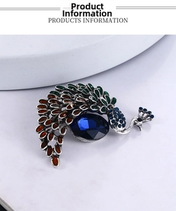 Détail d'une broche paon vintage avec pierre bleu foncé et strass colorés sur fond blanc