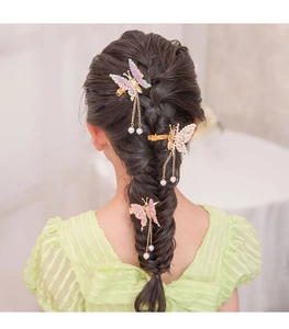 Detailed back view of three butterfly hair clips with pearl tassels on braided hair