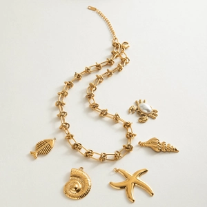 Detail van gouden schakelketting met marine bedeltjes zoals zeester en krab met parel