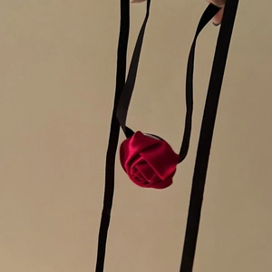 Detailed view of red satin rose choker with long black ribbon ties in vintage style