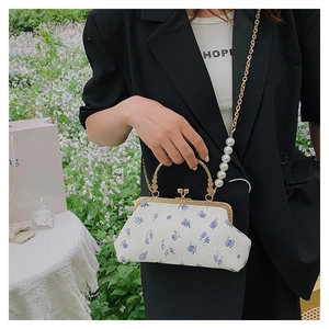 Detail of vintage white shell bag with purple floral pattern and pearl chain strap