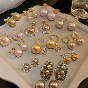 Detail view of pearl and rhinestone geometric earrings on a wave display tray