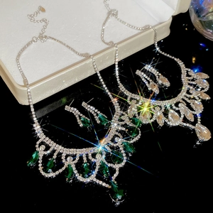 Close-up of sparkling water drop tassel jewelry sets with emerald and white stones