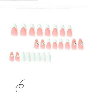 Detail of pink French press-on nails with white flowers and blue rhinestones set