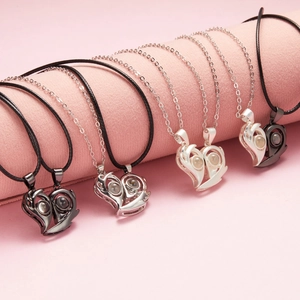 Close-up of four magnetic couple heart necklaces in black and silver on pink display