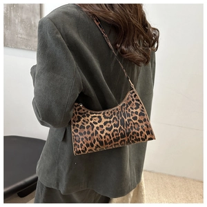 Detailed view of leopard print shoulder bag worn with a dark green corduroy blazer