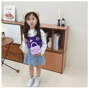 Girl wearing a purple mini crossbody bag with flower knit vest in a home setting