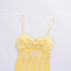 Yellow gingham sundress with bow tie design and smocked bodice on white background