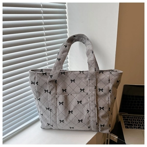 Detail of grey corduroy tote bag with black bow embroidery and quilted diamond pattern