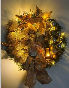 Detail of a gold Christmas wreath featuring a Nativity scene and warm LED lights