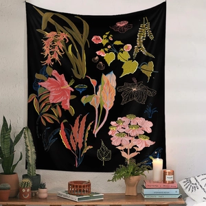Detail shot of black floral botanical tapestry hanging in a cozy living room setup