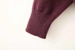 Close-up of soft knit sweater cuffs with premium ribbed texture in dark purple fabric