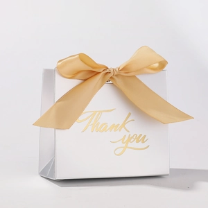 Detail of white wedding favor box with gold Thank You lettering and satin ribbon bow