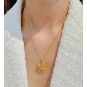 Elegant gold ginkgo leaf pendant necklace worn by a model on a minimalist background