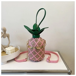 Close-up of pink pineapple crossbody bag with gold rivets and green leaf detail