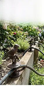 Detail of vintage cast iron bird on branch with rustic finish for garden wall decoration