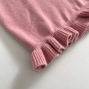 Pink knit top with delicate lettuce hem detail and soft ribbed texture for autumn style