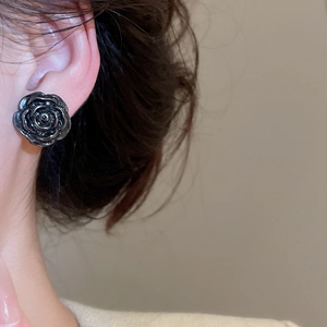 Close-up of a vintage black rose stud earring worn by a model for a chic look