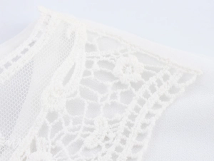 Macro detail of white floral lace embroidery and sheer mesh stitching on the blouse