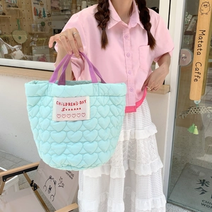 Détail du sac fourre-tout matelassé bleu clair avec motifs de cœur et anses mauves
