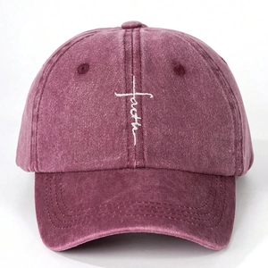 Close-up of embroidered white cross and faith script on washed burgundy cotton baseball cap
