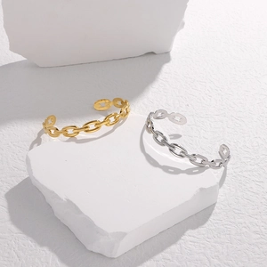 Dettaglio macro di bracciali a catena oro e argento su blocchi geometrici