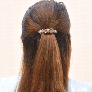Elegant pink-brown bow hair clip shown on model ponytail for hairstyle styling