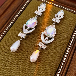 Close-up of silver tassel earrings with teardrop crystals and pearls on velvet