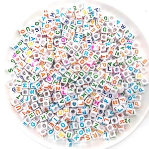 Top view of 6mm white acrylic alphabet cube beads with colorful letters in a bowl