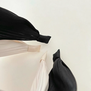 Detailed close-up of pleated headband ends in black and beige with soft fabric texture