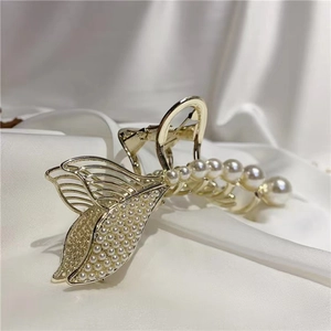 Close-up of golden mermaid tail hair claw with inlaid pearls on white silk