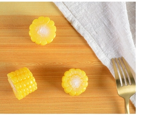 Detailed close-up of realistic yellow corn resin charms on a natural wood surface
