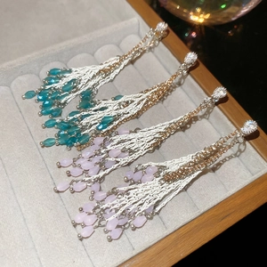 Vue détaillée de boucles d'oreilles à pompons avec pendentifs en cristal bleu et rose