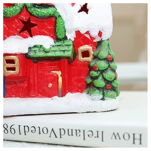 Detail of red ceramic Christmas house with snowy texture and warm glowing light