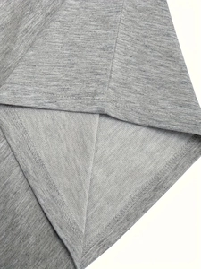 Gros plan du tissu en maille gris chiné montrant la double surpiqûre sur l'ourlet du t-shirt